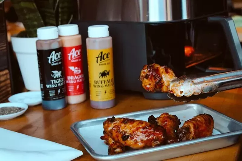 Image: three sauce bottles behind a tray of chicken wings