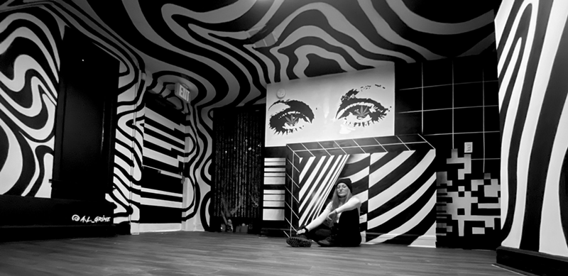 Image: Grimm sits within her full-room "Magical Mystery Tour" mural for the Marijuana Mansion.