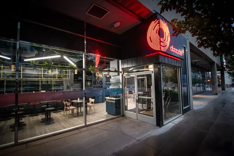 Image: the exterior of a club with red lettering spelling "dazzle."