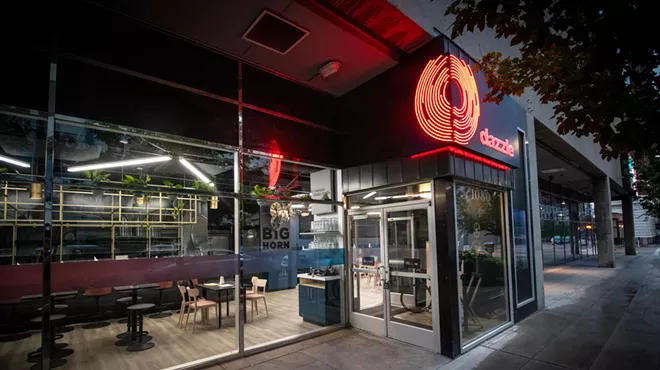 the exterior of a club with red lettering spelling "dazzle."