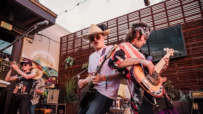 two men leaning on each other with guitars