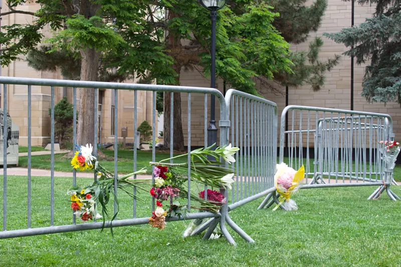 Image: memorial flowers line a fence in the grass