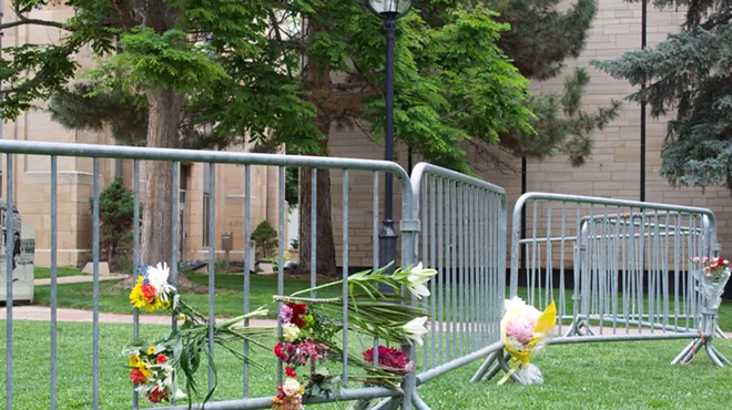 memorial flowers line a fence in the grass