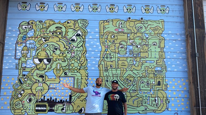 two men standing in front of a mural