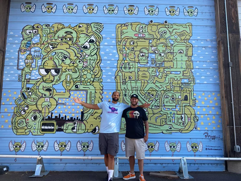 Image: two men standing in front of a mural