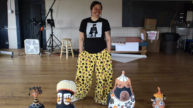 A woman stands with clay figurines