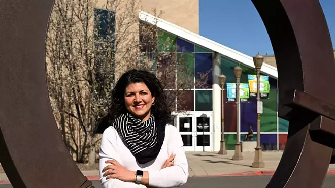 woman in white sweater in front of building.