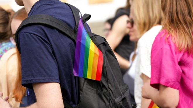 A student wearing a backpack with a small rainbow flag on it, symbolizing LGBTQ pride.