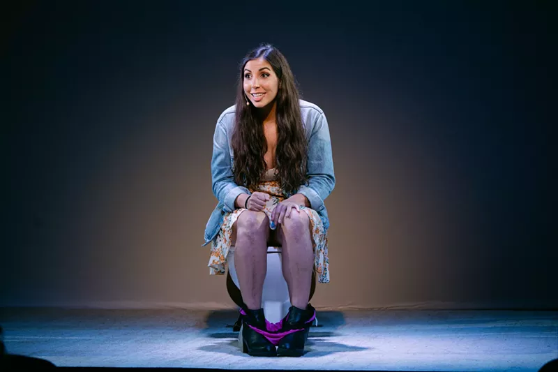 Image: woman on stage sitting on toilet