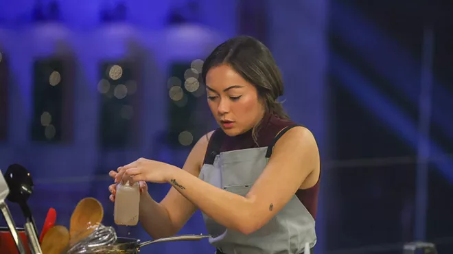 A woman cooks in a kitchen.