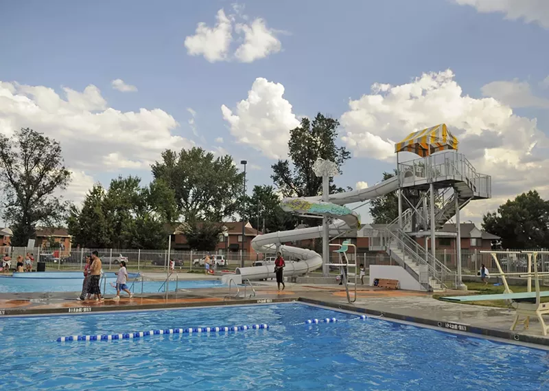 Image: A white water slide winds its way into a blue, rectangular pool.