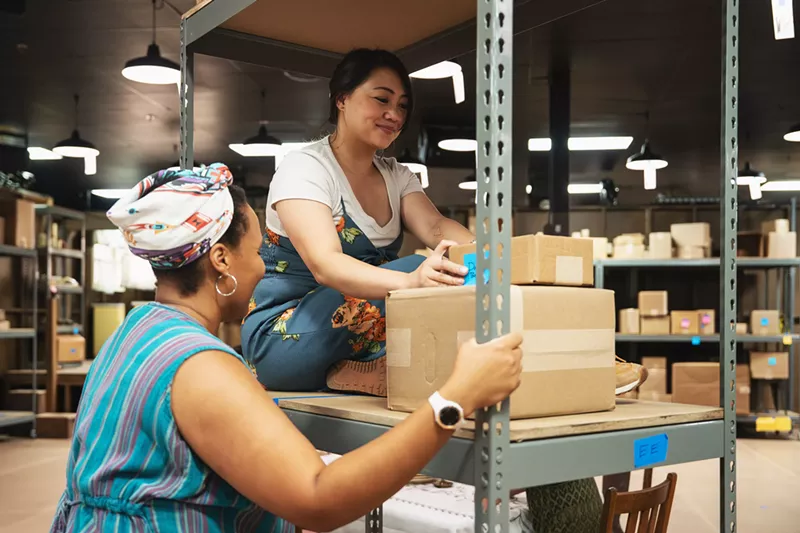 Image: People interact with a shelf of boxes