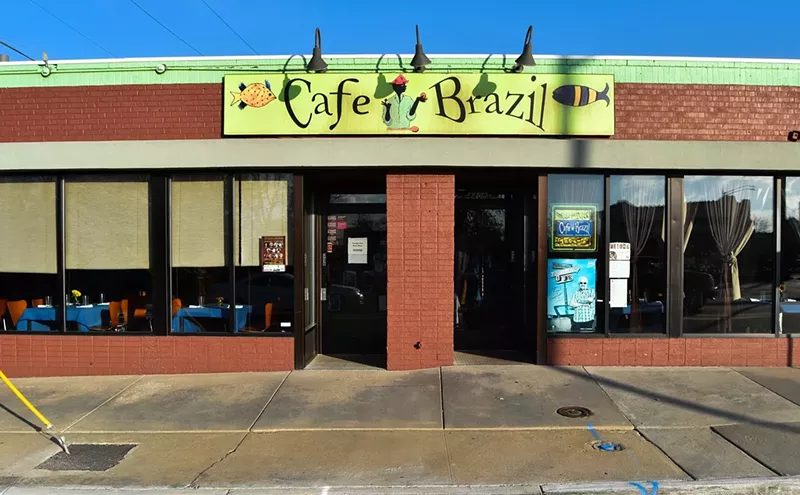 Image: The brick exterior of Cafe Brazil featuring a green restaurant sign