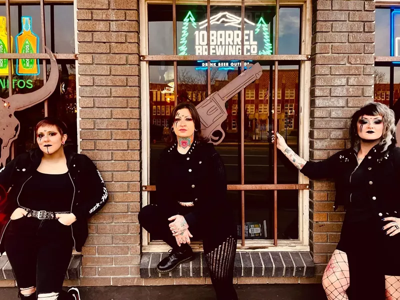 Image: three women standing outside of a brick building with big windows