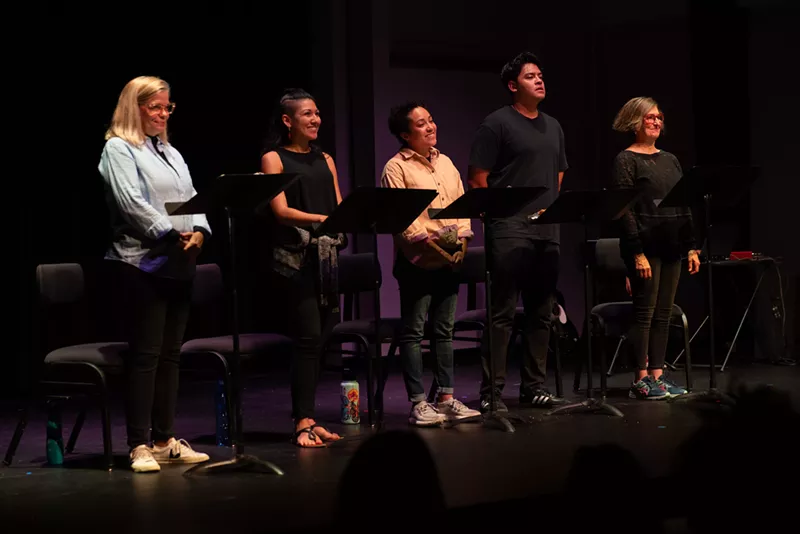 Image: Actors stand by microphones on a stage