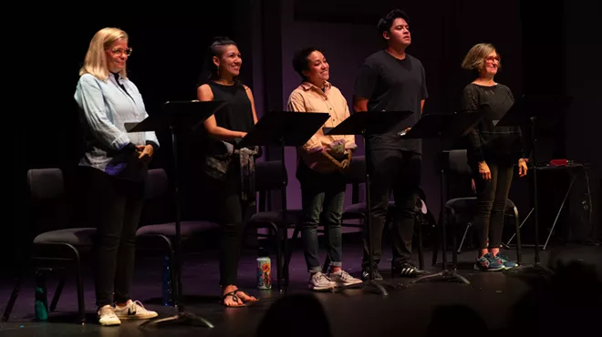 Actors stand by microphones on a stage