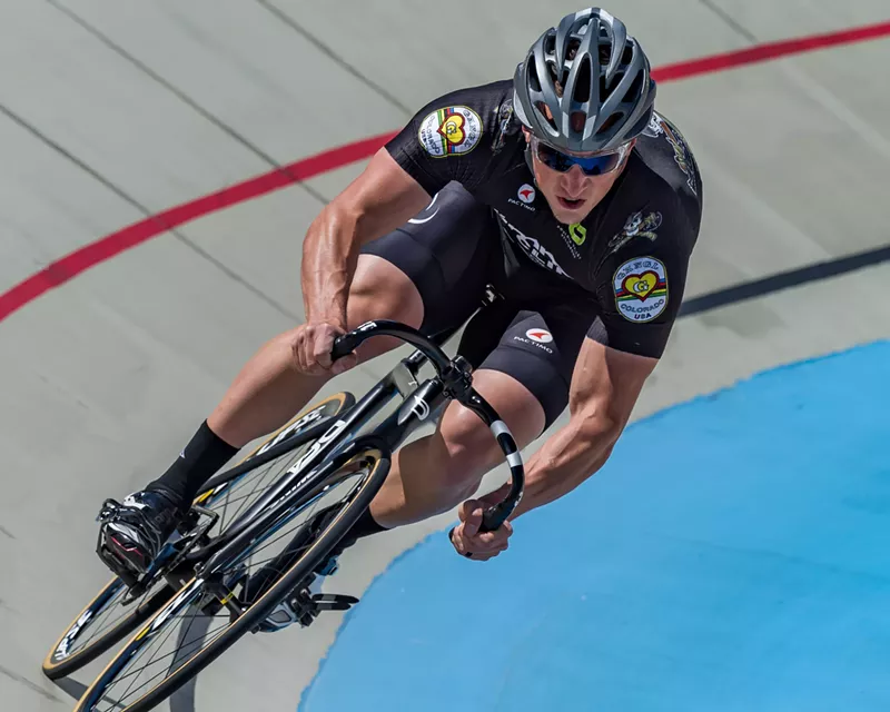 Image: A cyclist leans on a banked turn in the Boulder Valley Velodrome.