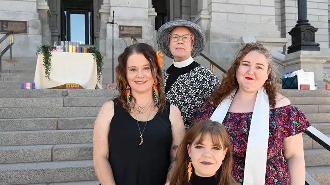 Four women stand in front of the State Capitol west steps.