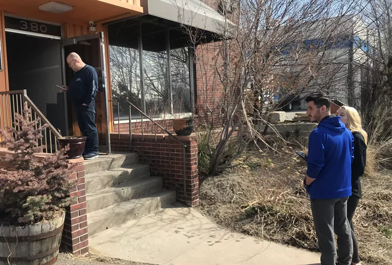 Image: Customers stand ten feet apart from each other while waiting in line at L'Eagle dispensary.