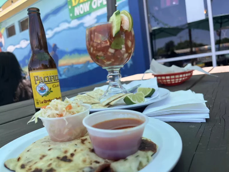 Image: beer in a bottle next to shrimp cocktail in a large glass