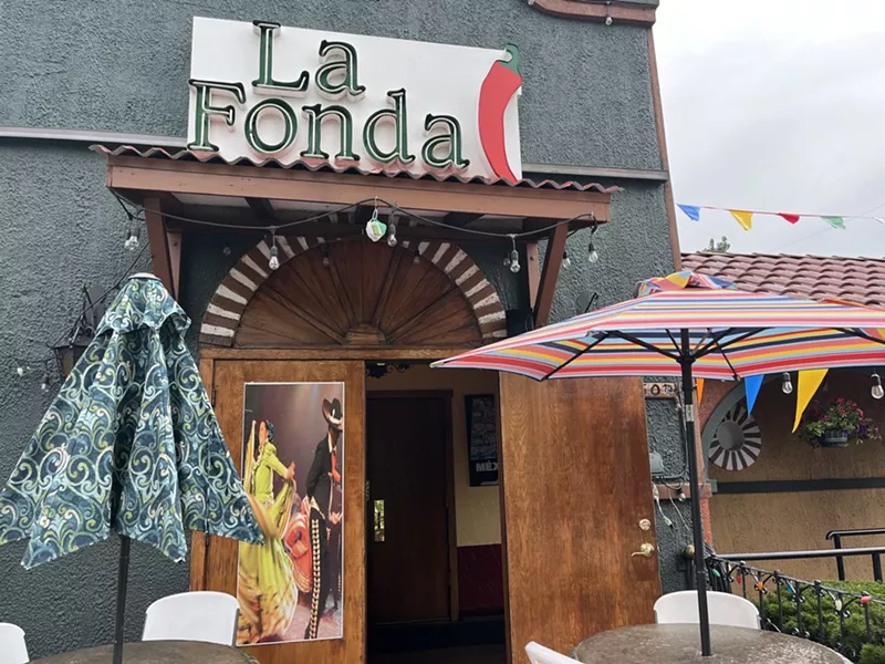 Image: an umbrella in front of the entryway to a restaurant