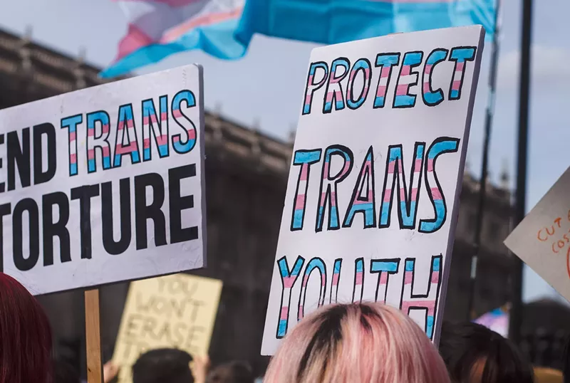 Image: A protester holds a sign that says "protect trans youth."