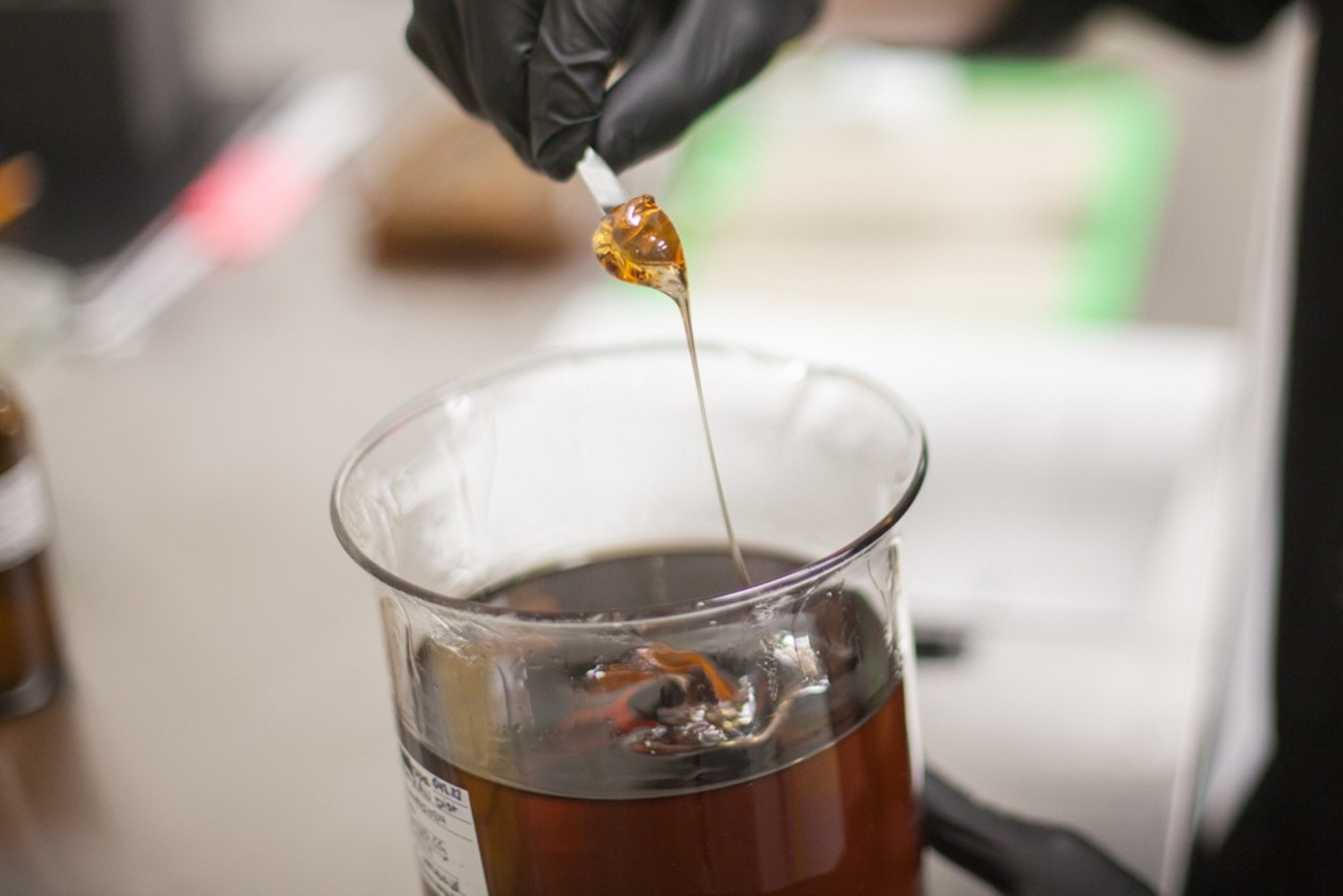 A lab worker stirs cannabis oil inside a commercial extraction facility.