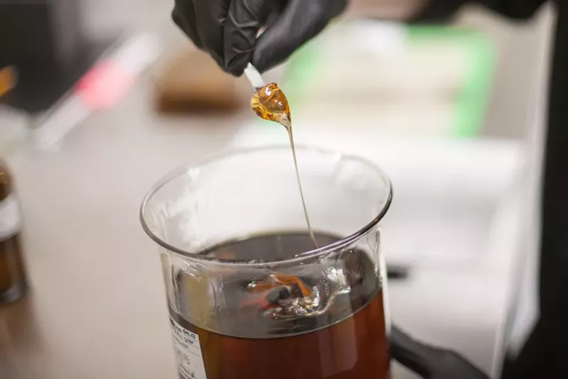 Image: A lab worker stirs cannabis oil inside a commercial extraction facility.