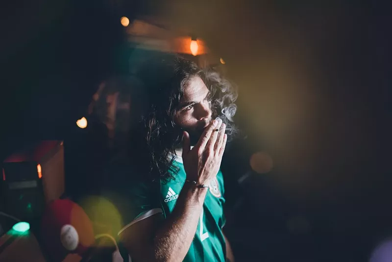 Image: Man in soccer jersey with long hair smokes marijuana