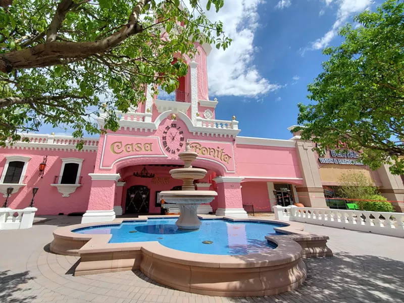 Image: a fountain in front of a pink building