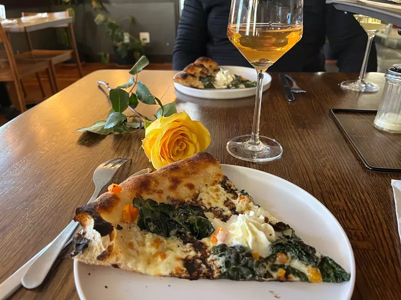 Image: slice of pizza, glass of wine and a yellow rose