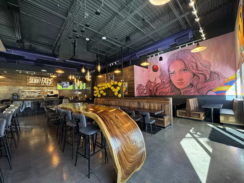 Image: a large wooden table inside a restaurant with murals
