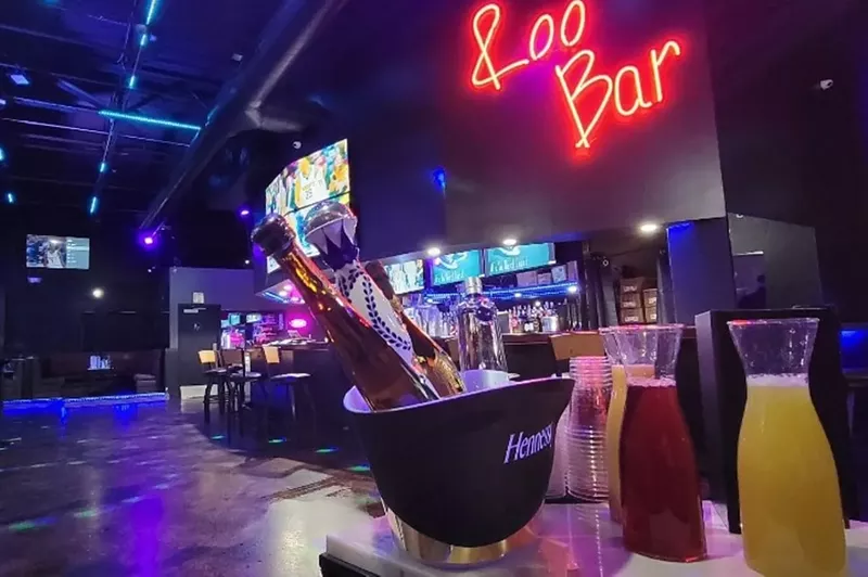 Image: A cocktail sits on a bar top in a darkened room.