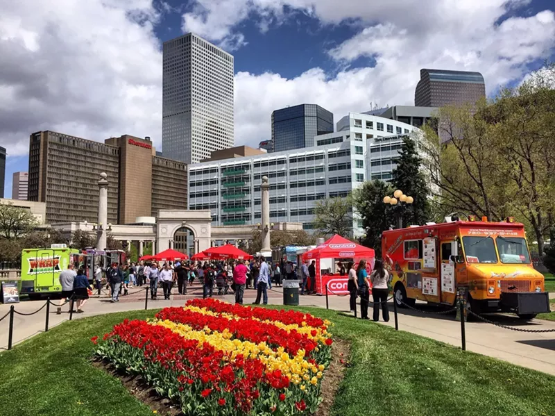 Image: downtown skyline behind food truck parked near a flower garden