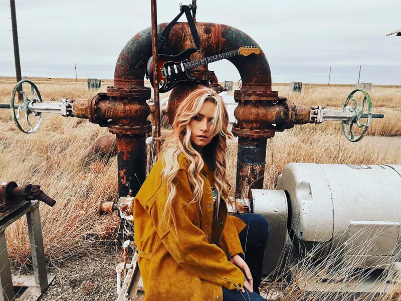 Image: blonde woman crouches in a field