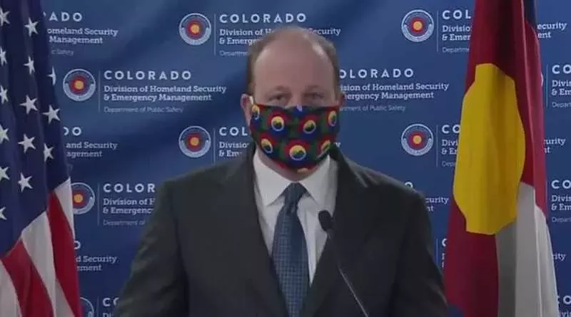 Image: Governor Jared Polis modeling a cloth face mask during the April 3 press conference.
