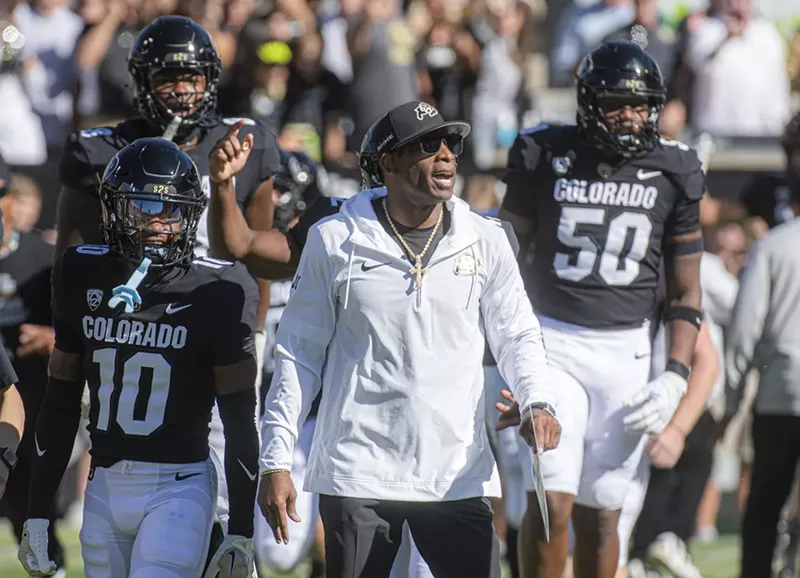 Image: CU football coach Deion Sanders surrounded by Buffalo football players.