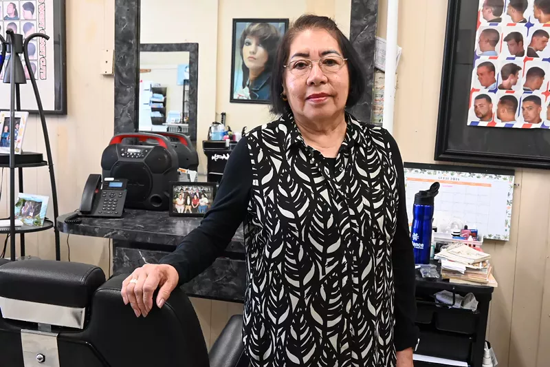 Image: A barber stands by her chair.