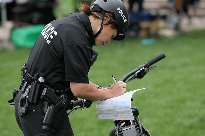 A Denver Police Department officer writes a citation during the annual 4/20 celebration at Civic Center Park in 2018.