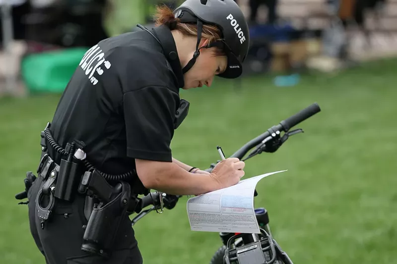 Image: A Denver Police Department officer writes a citation during the annual 4/20 celebration at Civic Center Park in 2018.