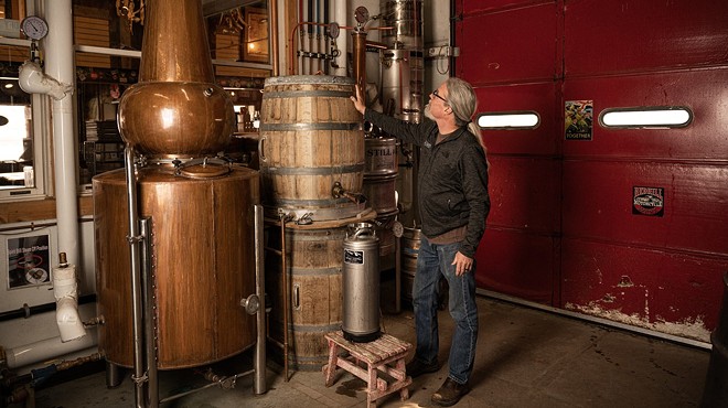 a man standing in front of distilling equipment