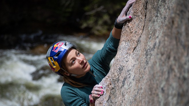 A woman climbs a rock.