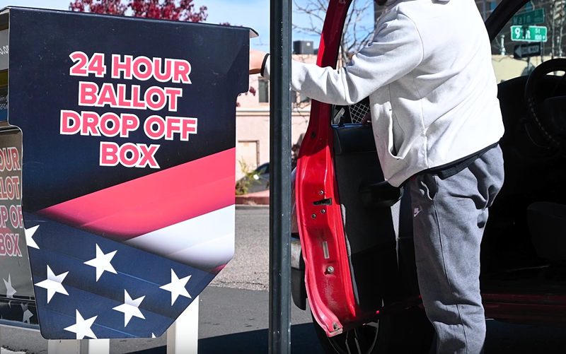Image: man drops off election ballot in dropoff box
