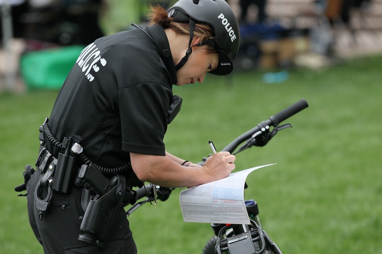 A Denver Police Department office writes a citation during the 4/20 Rally at Civic Center Park in 2017.