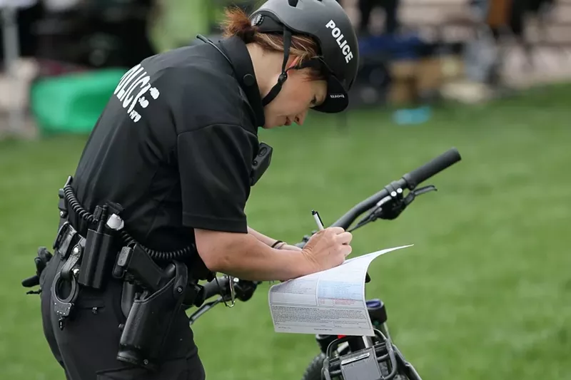 Image: A Denver Police Department office writes a citation during the 4/20 Rally at Civic Center Park in 2017.