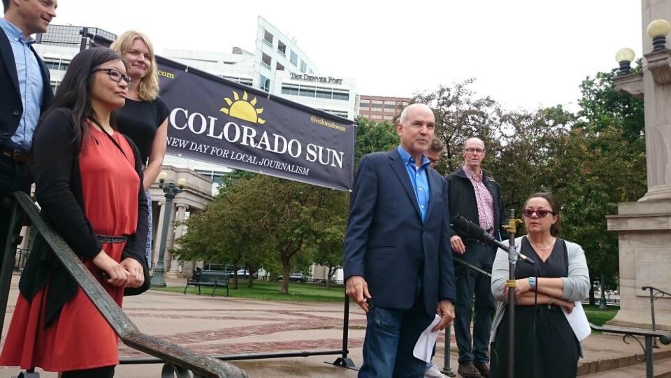 Colorado Sun editor Larry Ryckman stands before the microphone at a June 18 news conference held in Civic Center Park, in front of the old Denver Post building. Left to right: John Ingold, Tamara Chuang, Jennifer Brown, Ryckman, Jason Blevins (partially obscured), Kevin Simpson and Dana Coffield.