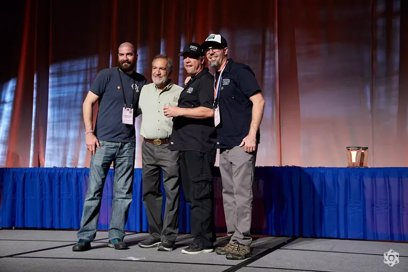 Image: four men standing on a stage