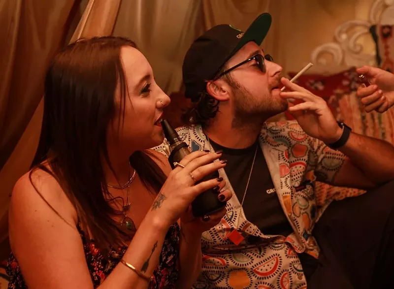 Image: Man smokes a joint as a woman dabs a Puffco Peak