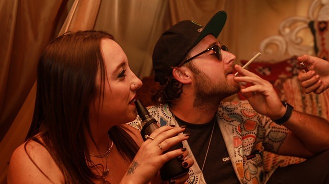 Man smokes a joint as a woman dabs a Puffco Peak