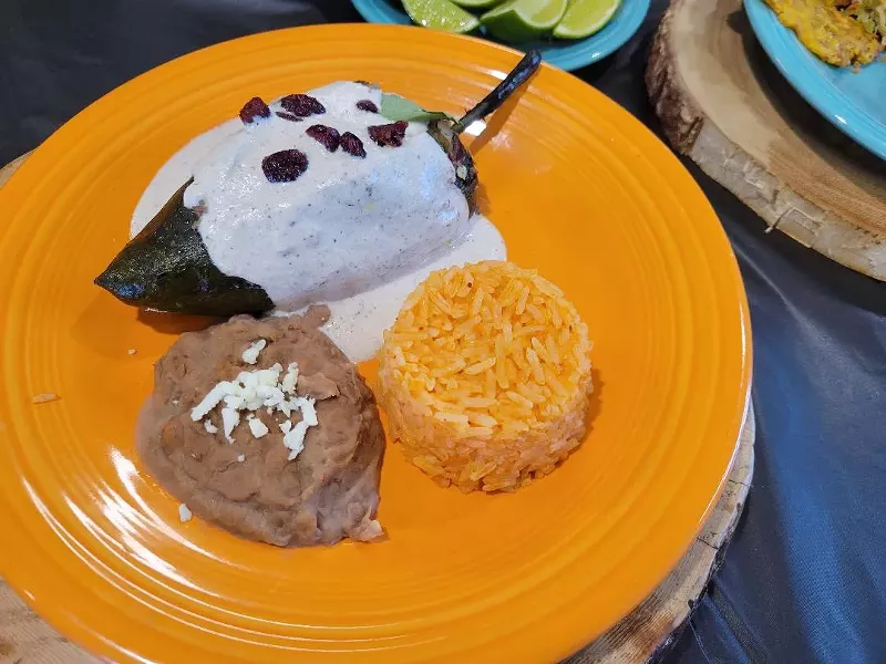 Image: orange plate with chile relleno, rice and beans